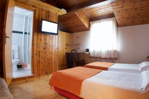a bedroom with two beds and a window and a television at Locanda San Lorenzo in Puos dʼAlpago