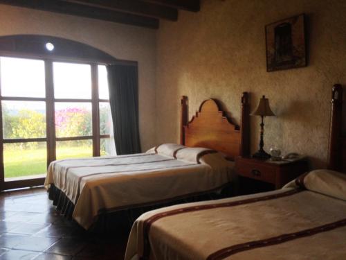 a hotel room with two beds and a window at Hotel Posada de Don Rodrigo Panajachel in Panajachel