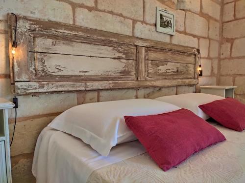 a bed with two pillows and a brick wall at Masseria Salentina Costarella in Borgagne