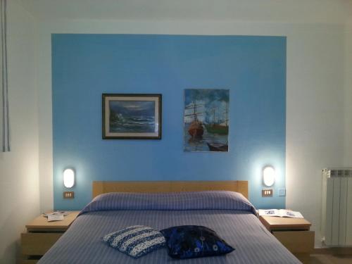 a bedroom with a blue wall with a bed and two lights at Hotel Pensione Signorini in Castiglioncello