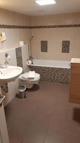 a bathroom with a toilet and a sink and a tub at Landhotel Klempau in Lübeck