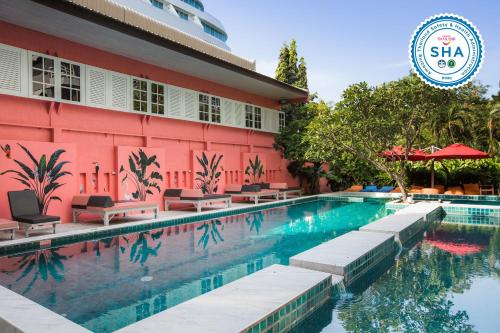 a swimming pool in front of a pink building at Sandalay Resort in Pattaya
