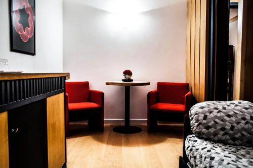 a waiting room with two red chairs and a table at Locanda San Lorenzo in Puos dʼAlpago
