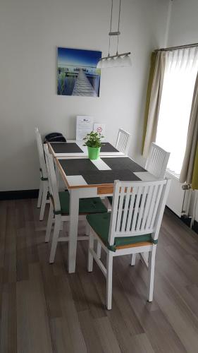 a dining room table with white chairs and a table with a plant at Landhotel Klempau in Lübeck