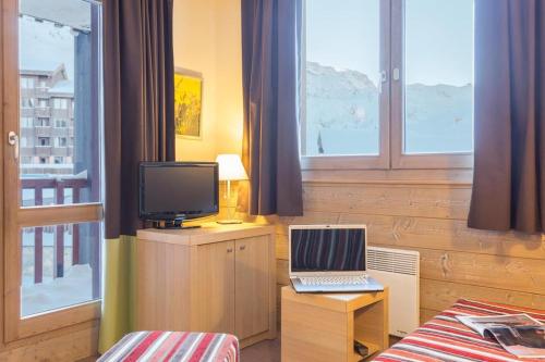 1 dormitorio con ordenador portátil, TV y ventanas en Résidence Les Gémeaux - Belle Plagne, en La Plagne