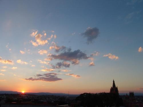 a sunset over a city with a clock tower at Casa del Tio Hotel Boutique in San Miguel de Allende