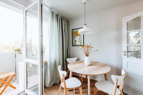 a small dining room with a wooden table and white chairs at Gdynia Square Apartment in Gdynia