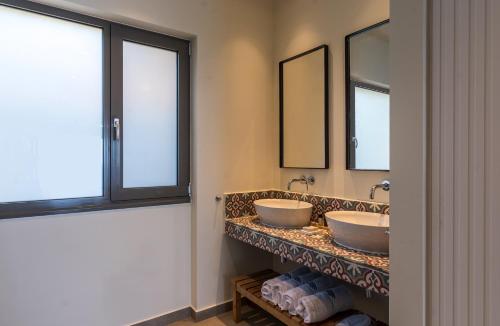 two sinks in a bathroom with two mirrors at Amphitheatre Suites in Palaiochora