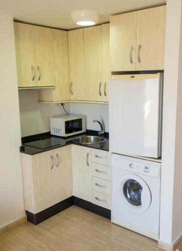 a kitchen with a washing machine and a microwave at Aparthotel Villas La Manga in La Manga del Mar Menor