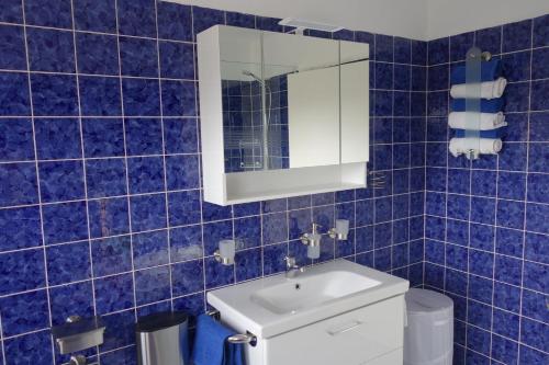 a blue tiled bathroom with a sink and a mirror at Ferienwohnung Waldstuben in Goldenstedt