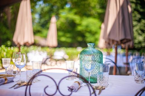 a table with a blue vase and glasses on it at Chateau des Ayes - Chambres & suites in Saint-Étienne-de-Saint-Geoirs