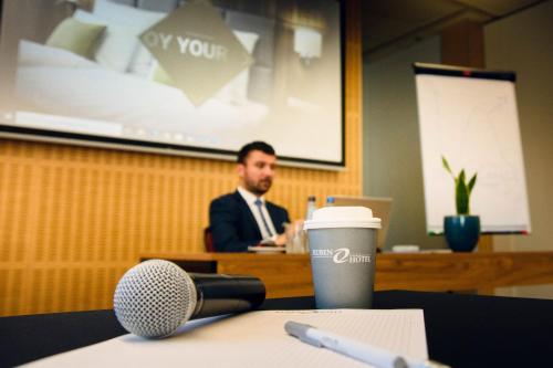 a man sitting at a table in a room with a microphone at Ruben Hotel Zielona Góra in Zielona Góra