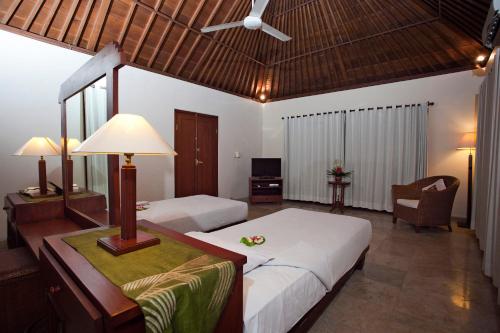 a bedroom with two beds and a table with a lamp at Natah Bale Villas in Sanur