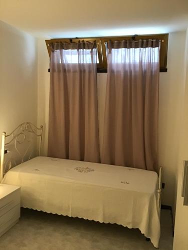 um quarto com uma cama branca e uma janela em Casa-Lisa seminterrato em Miggiano