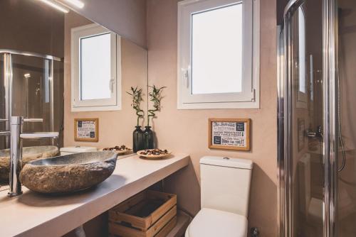 a bathroom with a sink and a toilet and windows at Acropolis View - Living Stone Sapphire Apartment in Athens
