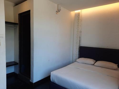 a small bedroom with a white bed and a wall at Hotel Cipta Impian in Kampong Keriting