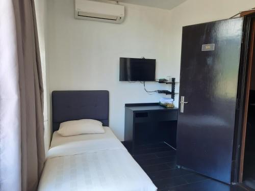 a room with a bed and a desk and a television at Hotel Cipta Impian in Kampong Keriting