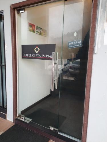 a glass door of a building with a sign on it at Hotel Cipta Impian in Kampong Keriting