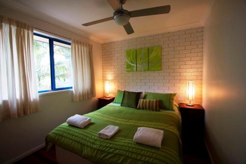 a bedroom with a green bed with two pillows at Byron Bay Accom Unit 3 41 Childe Street - Belongil Beach Apartment in Byron Bay