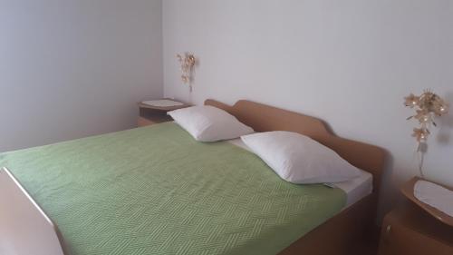 sypialnia z zielonym łóżkiem z 2 poduszkami w obiekcie Apartmani Slavka w Baskiej Vodzie