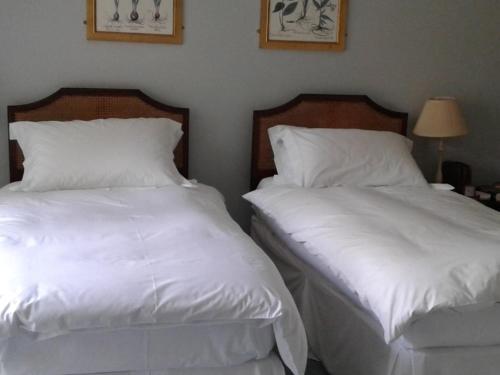 two beds in a room with white sheets and pillows at Well Cottage B and B in Cirencester