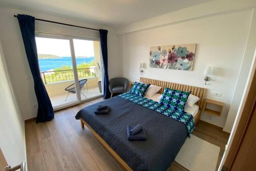a bedroom with a bed with blue pillows and a balcony at Apartment Sandra (2+2) with a breathtaking view 2 in Vis