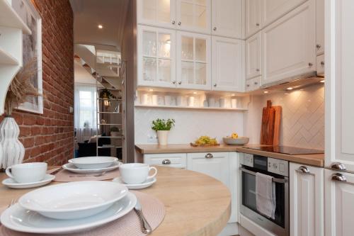 a kitchen with white cabinets and a wooden table at Apartamenty Profesorskie in Szczecin