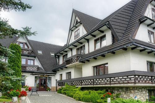 a large white house with a black roof at Dom wczasowy Anna Maria in Sierockie