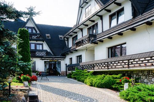 a building with a courtyard with flowers and plants at Dom wczasowy Anna Maria in Sierockie