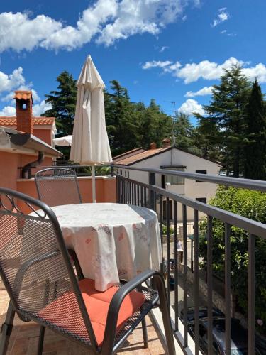 a table and an umbrella on a balcony at Apartments Tajana in Novigrad Istria