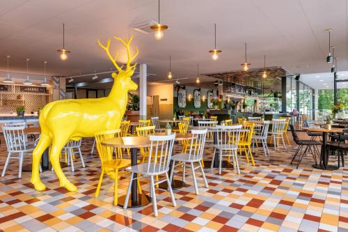 a yellow deer statue in a restaurant with tables and chairs at Stayokay Hostel Maastricht in Maastricht