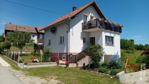 a white house with a balcony and a yard at Apartment Dolores in Smoljanac