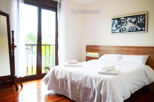 a bedroom with a white bed with two towels on it at Chalet Tina Mayor: amplio jardín y tranquilidad muy cerca de la playa in Pesués
