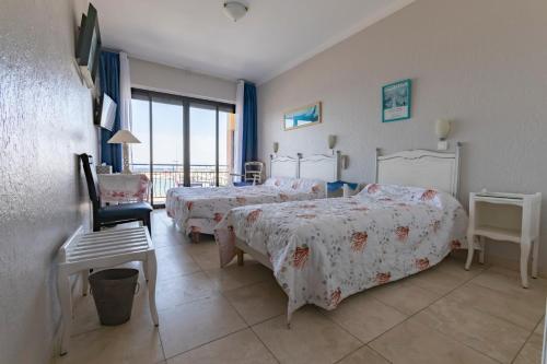 a hotel room with two beds and a balcony at Hôtel Les Alizés in Cavalaire-sur-Mer