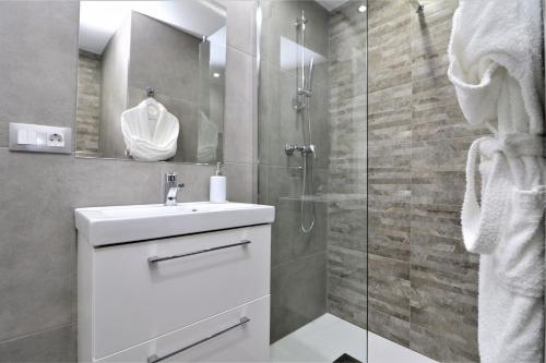 W łazience znajduje się umywalka i przeszklony prysznic. w obiekcie Alameda Beach Centro w mieście Benidorm