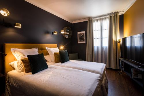a bedroom with two beds and a flat screen tv at Hôtel - Restaurant Le Globe in Meursault