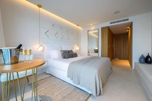 a white bedroom with a bed and a wooden table at The Island Concept Luxury Boutique Hotel Heated Pool in Agios Nikolaos