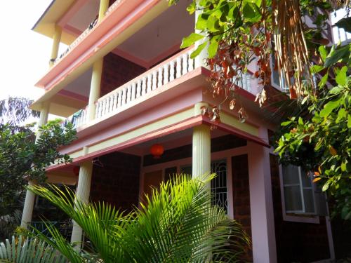 a pink house with a balcony on top of it at Namaste Yoga Farm in Gokarna