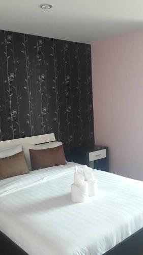 a bedroom with a large white bed with a black wall at Nalin Place in Ranong