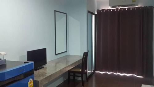 a room with a desk with a television and a curtain at Nalin Place in Ranong