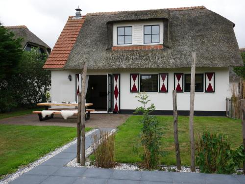 a thatched cottage with a picnic table in front of it at Buitenplaats Villa Deluxe in Callantsoog