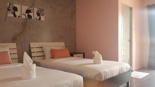 two beds in a bedroom with pink walls at Nalin Place in Ranong