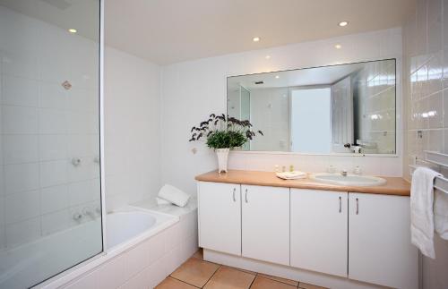 un bagno con vasca, lavandino e specchio di Gemini Resort a Caloundra