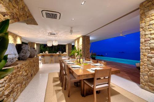 a dining room with a table and a stone wall at Baan Sang in Taling Ngam Beach