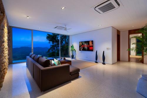 a living room with a couch and a large window at Baan Sang in Taling Ngam Beach