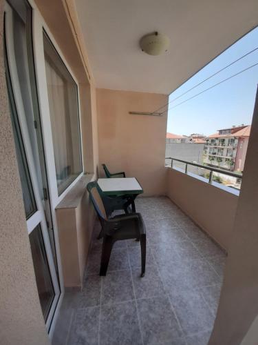 a balcony with a table and a chair and a window at Guest House Damyanov in Ravda