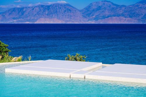 a pool with a view of the ocean and mountains at The Island Concept Luxury Boutique Hotel Heated Pool in Agios Nikolaos