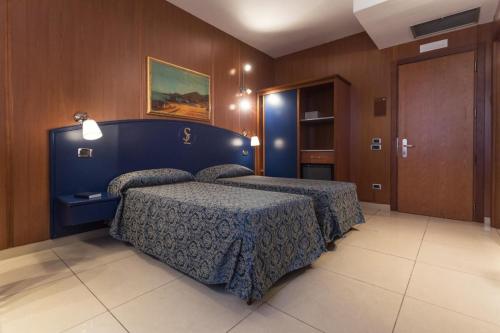 a hotel room with two beds and a door at Hotel San Luca in Battipaglia