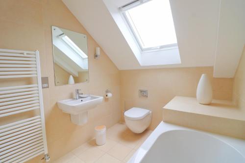 ein Badezimmer mit Toilette und Waschbecken und einem Oberlicht in der Unterkunft Beachside apartment, sea views in Saint Merryn