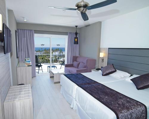 a hotel room with a large bed and a balcony at Hotel Riu Palace Meloneras in Maspalomas